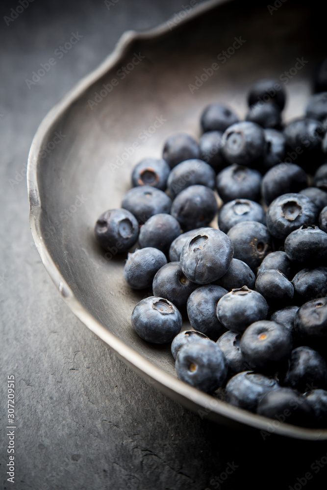 Part of tin bowl with blueberries (Vaccinium myrtillus) on slate Part of tin bowl with blueberries (Vaccinium myrtillus) on slate