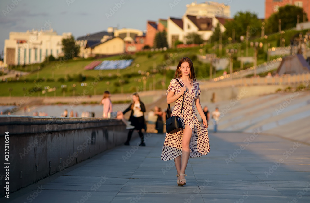Girl with coffee is walking along the promenade