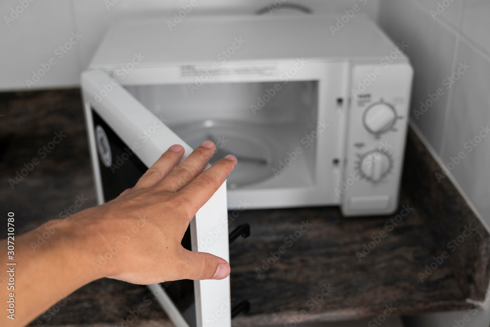 Man hand holdind a door of microwave in a kitchen for cooking or heating a dish. Man hand holdind a door of microwave in a kitchen for cooking or heating a dish.