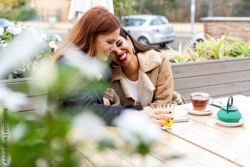 Two happy female friends drinking tea outdoors at a coffee shop Two happy female friends drinking tea outdoors at a coffee shop