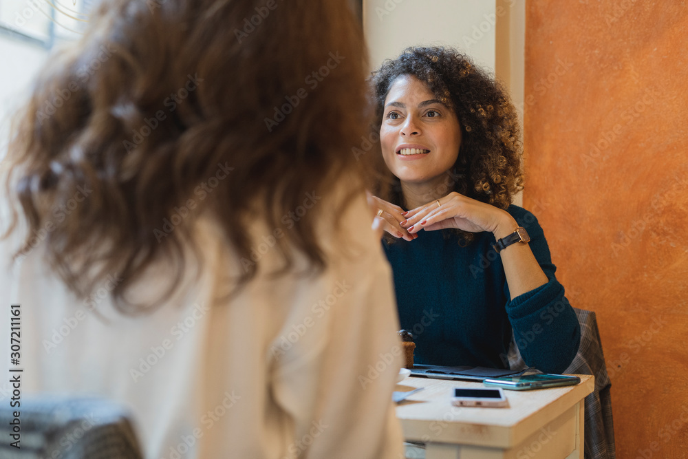 Two women meeting and talking in a cafe