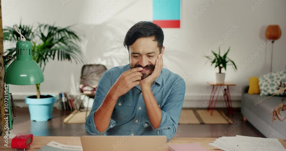Cute Hispanic adult man getting excited email and smiling feeling happy at home living room, casual bearded guy fixing mustache and leaning on arms looking straight dreaming about lovely girlfriend Cute Hispanic adult man getting excited email and smiling feeling happy at home living room, casual bearded guy fixing mustache and leaning on arms looking straight dreaming about lovely girlfriend