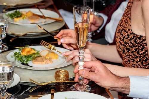 Fototapeta Naklejka Na Ścianę i Meble -  Group of people sitting at a table eating foie gras and drinking champagne