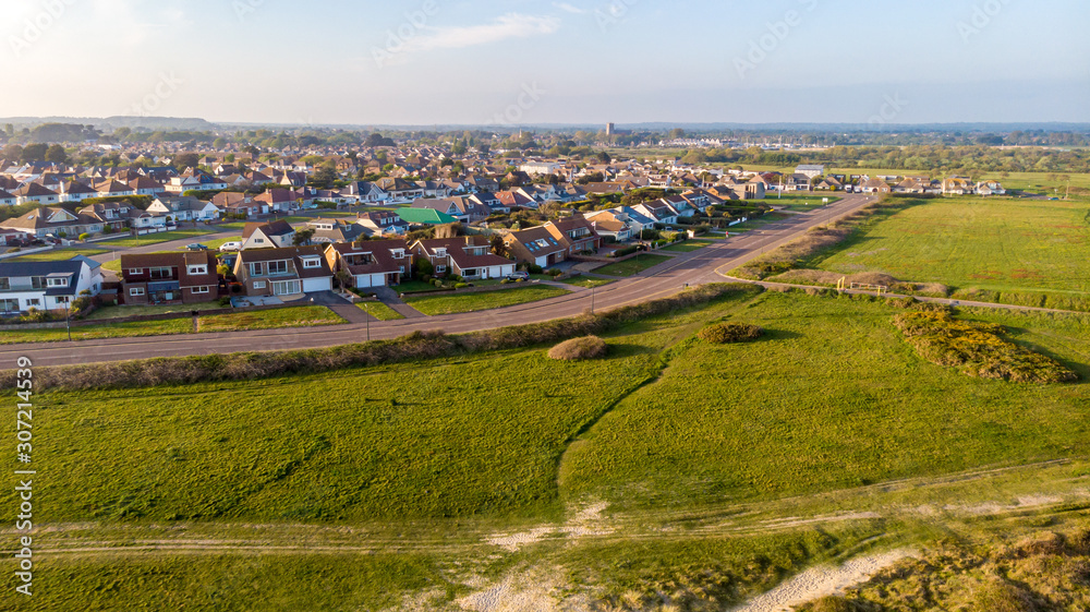 An aerial view of a coastal urban area along a park under a blue sky and white clouds