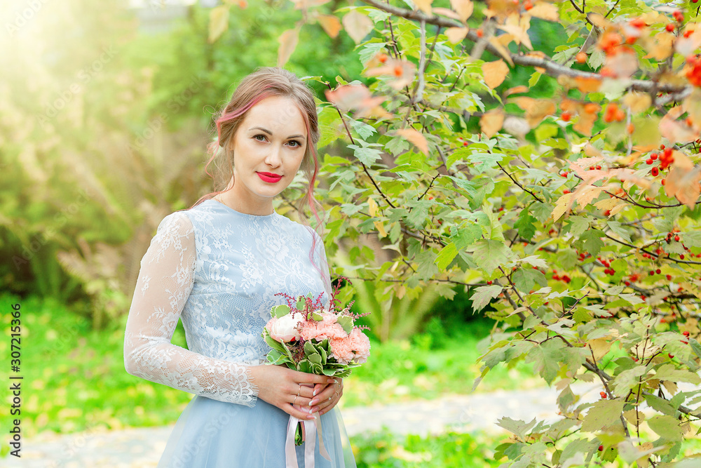 bride in the sun in a park with a bouquet in her hands bride in the sun in a park with a bouquet in her hands