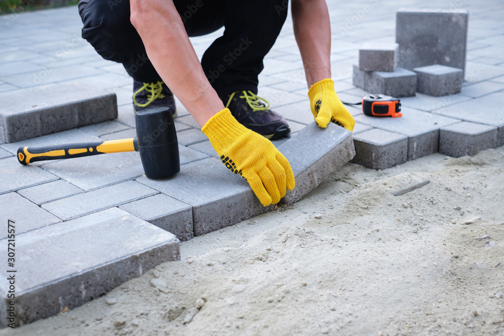 The master in yellow gloves lays paving stones The master in yellow gloves lays paving stones