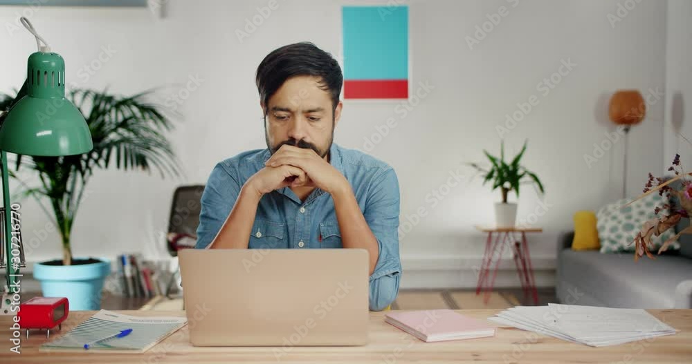 Disappointed Hispanic man feeling angry and funny expressing anger at modern home office, sorrowful young male dressed in casual jeans shirt can not concentrate on work because of domestic sad problem