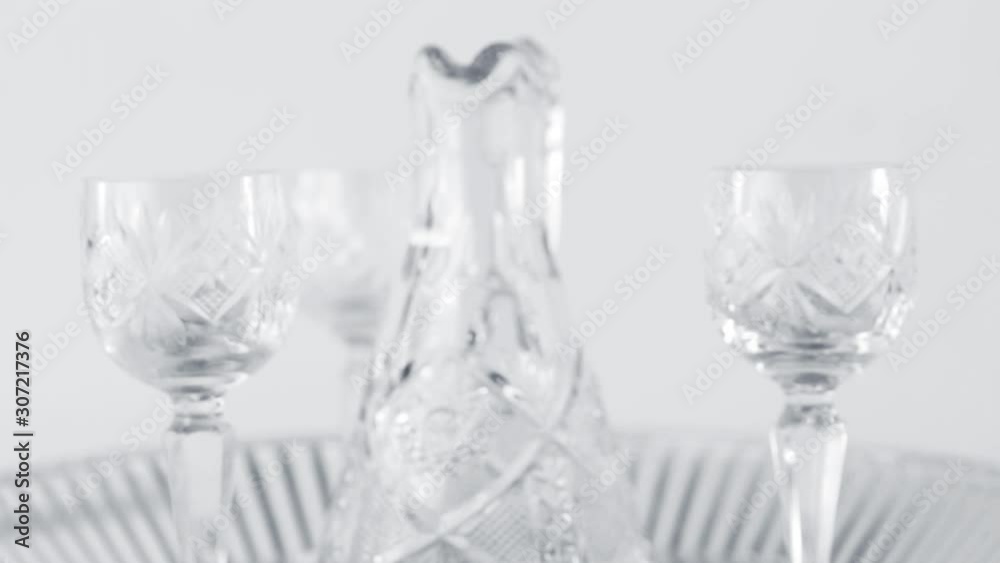 Crystal decanter and three wine glass for vodka placed on the cut glass dish