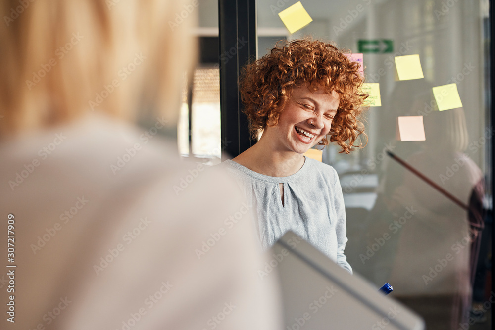 © Westend61 - Laughing businesswoman with sticky notes at glass pane in office © Westend61 - Laughing businesswoman with sticky notes at glass pane in office