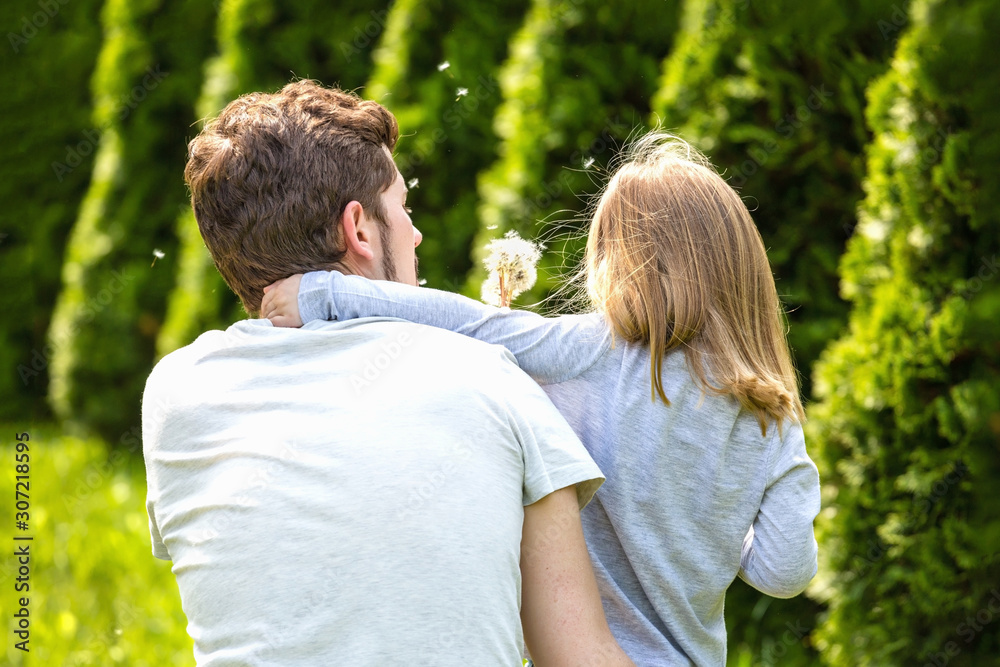 Back view. Father and daughter blowing dandelion flowers. Back view. Father and daughter blowing dandelion flowers.