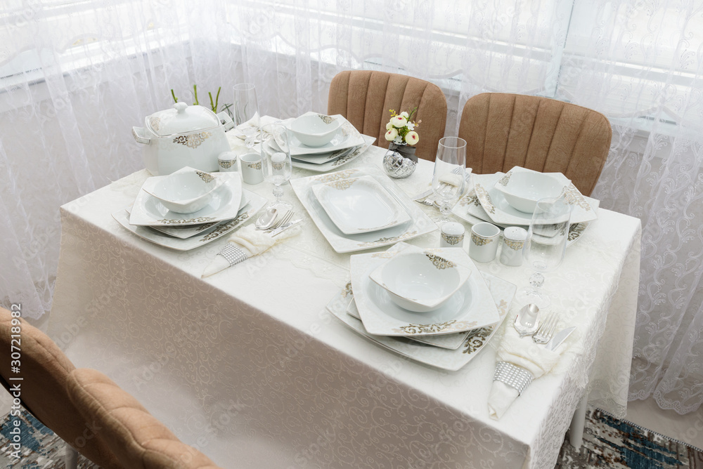 Elegant decoration of table. Porcelain plates, silver cutlery and crystal glasses.