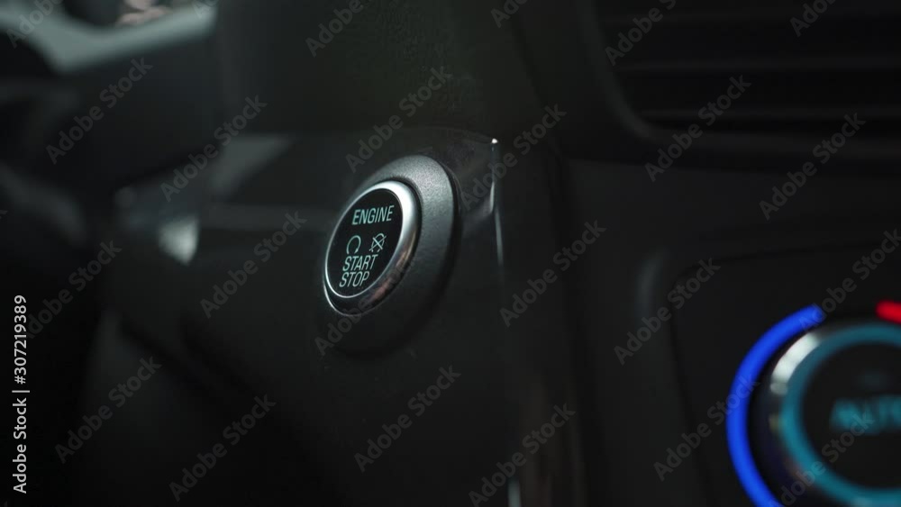 Male hand pushes engine start stop button in a modern car interior Male hand pushes engine start stop button in a modern car interior