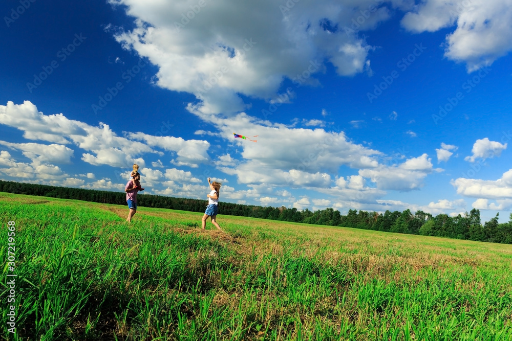 Mother, father and daughter are flying a kite in the field. Mother, father and daughter are flying a kite in the field.