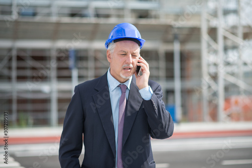 Architect manager talking on the cellphone in front of construction site