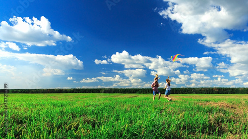Mother, father and daughter are flying a kite in the field.