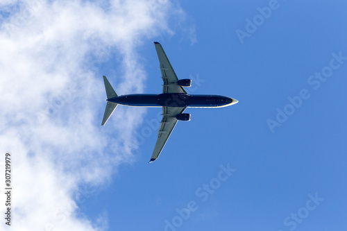 Low angle view of plane against sky, close up fling. Blue plane, low cost flights company, passenger airplane flight against blue background below view