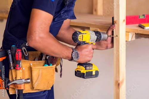 Handyman with headphones works with drill does repair. photo