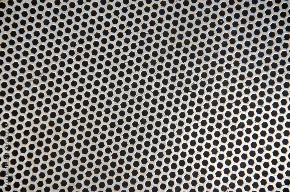 Abstract metallic perforated dark background with metal mesh effect texture.