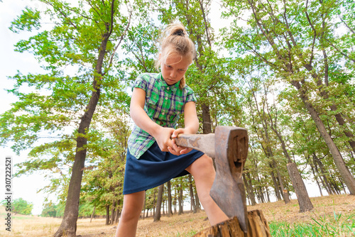 Angry and serious girl with an ax chopping wood in the forest, wide-angle photo view from below.