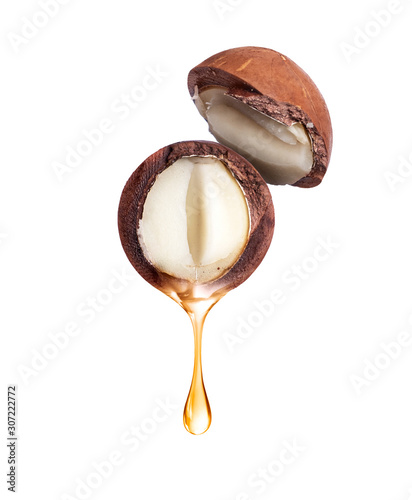Oil dripping from macadamia nut close-up, isolated on a white background