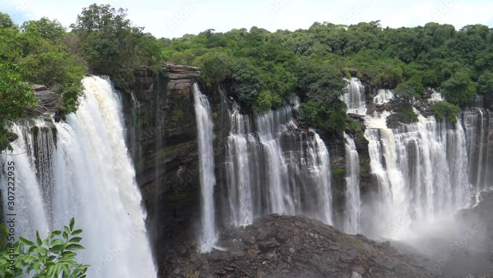 Pan from the Kalandula Falls spraying water over bushes and tart-like rocks in Angola Pan from the Kalandula Falls spraying water over bushes and tart-like rocks in Angola