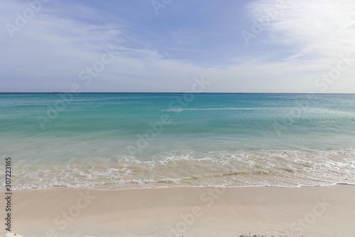 White sand beach and turquoise waves. Turquoise sea water and blue sky. Eagle Beach of Aruba Island. Beautiful backgrounds.