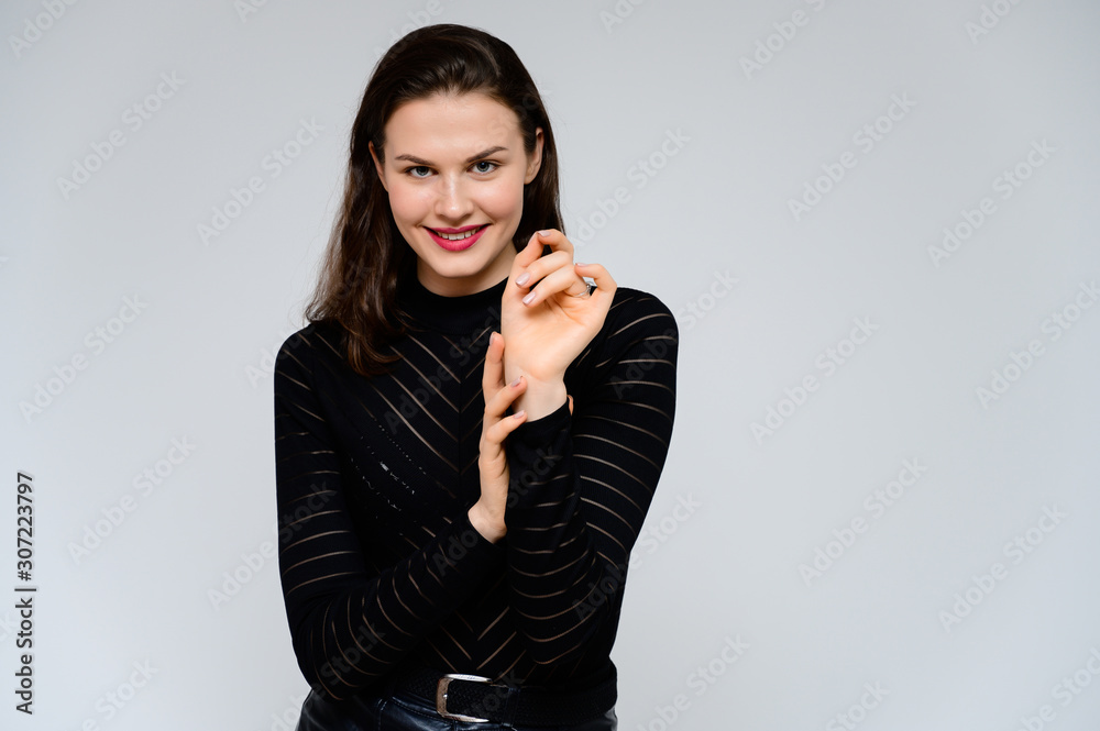 Concept adult girl on a white background. Large photo of a pretty brunette girl in a black sweater smiling and showing different emotions in different poses right in front of the camera. Concept adult girl on a white background. Large photo of a pretty brunette girl in a black sweater smiling and showing different emotions in different poses right in front of the camera.