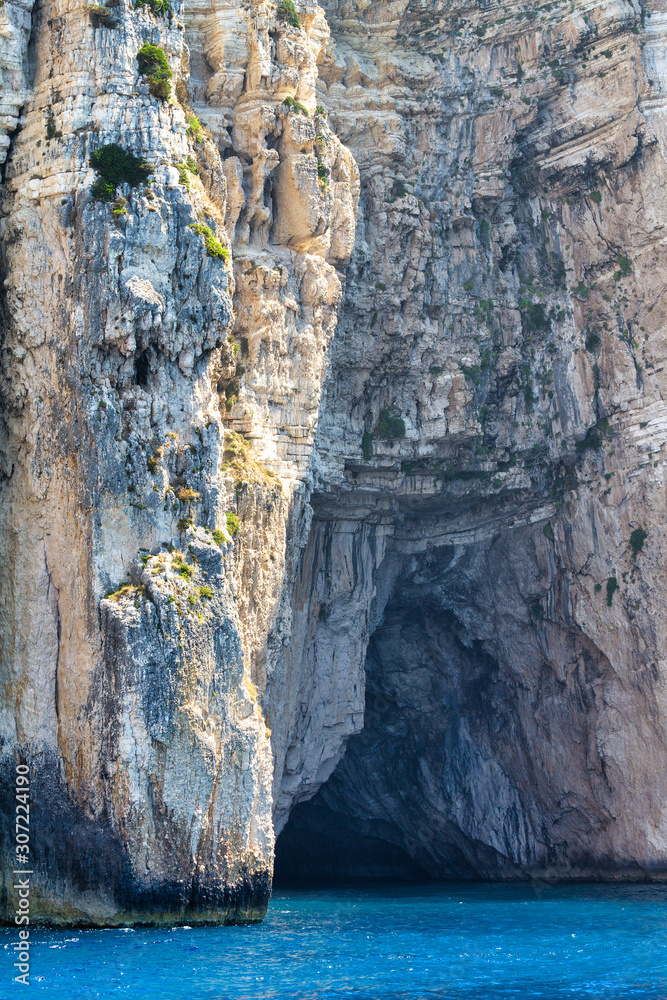 Steep cliffs with sea caves on the coast of the Greek island of Paxos, nearby Corfu island, Europe.