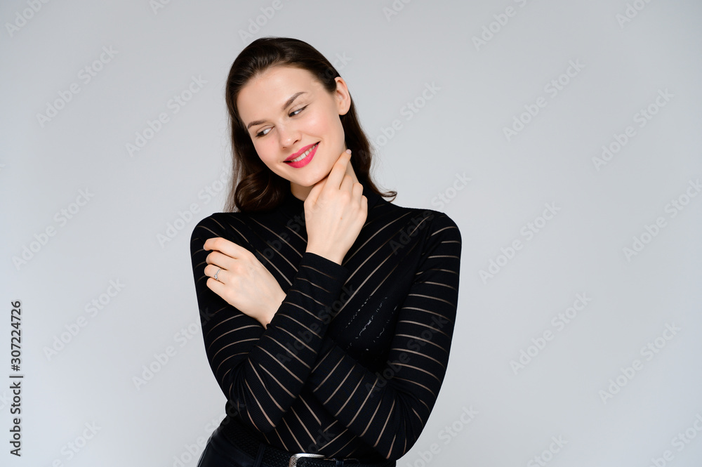 Concept adult girl on a white background. Large photo of a pretty brunette girl in a black sweater smiling and showing different emotions in different poses right in front of the camera. Concept adult girl on a white background. Large photo of a pretty brunette girl in a black sweater smiling and showing different emotions in different poses right in front of the camera.