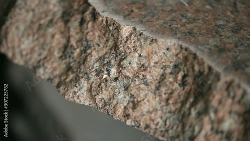 Uneven section of granite raw stone slab, closeup view.