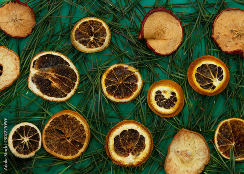 Green background with pine needles and dry oranges. Happy New year and Christmas composition. Trendy color. Copy space.