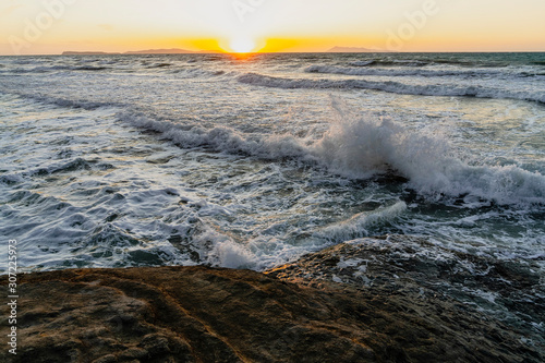 Bright sea sunset. The waves crash into the rock. The sea wave breaks into splashes and white foam. Never-ending beauty of nature. Logas Beach, Sidari, Corfu, Greece, Europa.