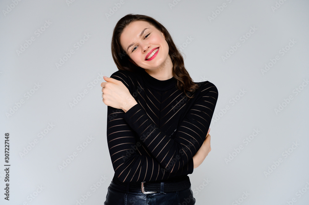 Concept adult girl on a white background. Large photo of a pretty brunette girl in a black sweater smiling and showing different emotions in different poses right in front of the camera. Concept adult girl on a white background. Large photo of a pretty brunette girl in a black sweater smiling and showing different emotions in different poses right in front of the camera.