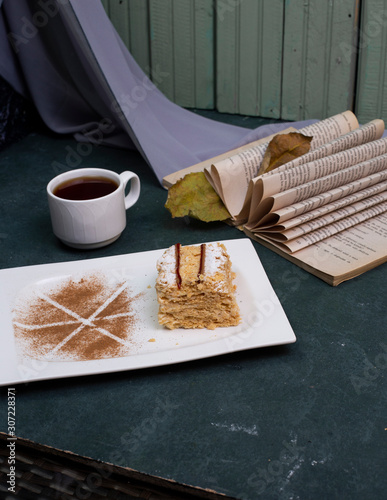 cup of tea, book and sweet cake with dark blue background