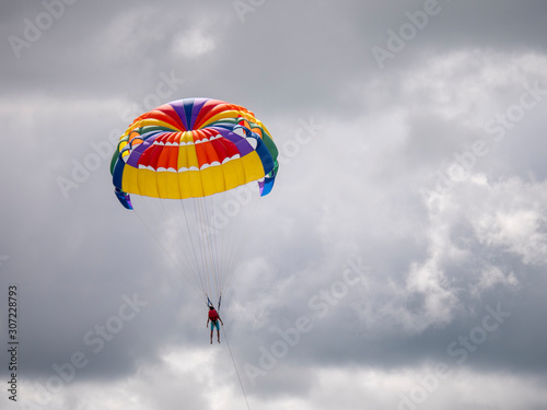 Anonymous paracel rider flies in free endless cloudy sky empty space colorful