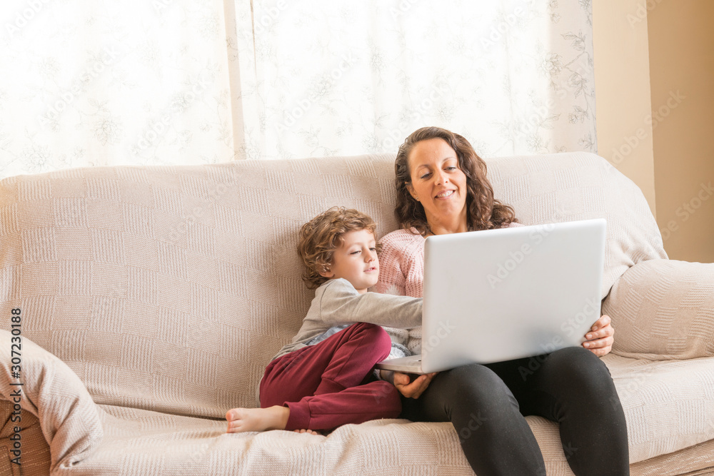 Child and woman sitting on a sofa watching a laptop. Child and woman sitting on a sofa watching a laptop.