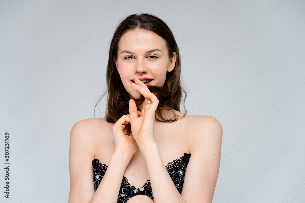 Concept adult girl on a white background. Large photo of a pretty brunette girl with excellent facial skin in a black bra smiles and shows different emotions in different poses. Concept adult girl on a white background. Large photo of a pretty brunette girl with excellent facial skin in a black bra smiles and shows different emotions in different poses.