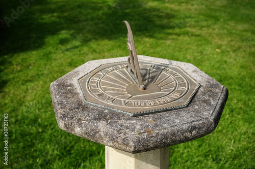 Sundial on stone plinth with inscription "tempus fugit" latin for time flies