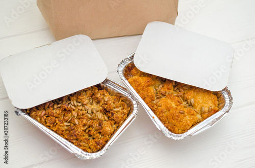 Indian food, fruit pies, subhadra and mithai, in foil plates on a white background, sprinkled with seeds, near paper bag, mockup
