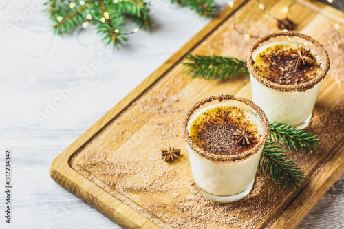 Eggnog with cinnamon and nutmeg for Christmas and winter holidays. Homemade eggnog in glasses on wooden table surface, shallow depth of the field, copy space.