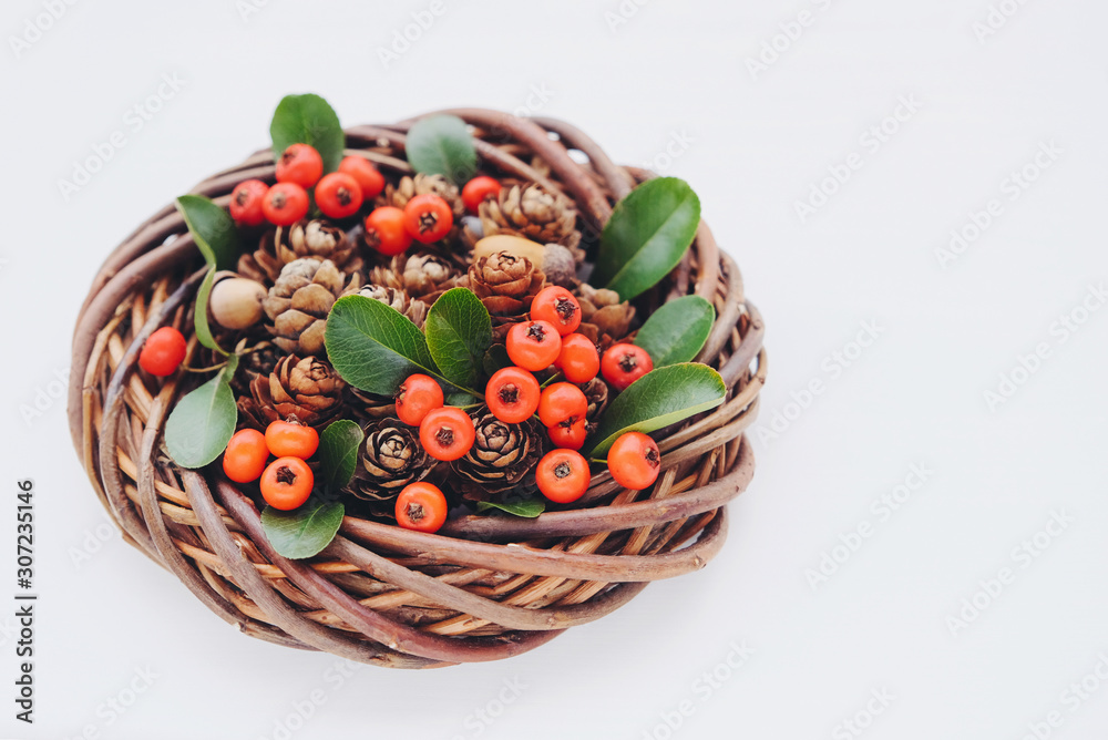 Beautiful wooden Christmas wreath made of willow branches with pine cones and red cotoneaster berries on white wooden background. Space for text. Zero waste holiday concept. Beautiful wooden Christmas wreath made of willow branches with pine cones and red cotoneaster berries on white wooden background. Space for text. Zero waste holiday concept.