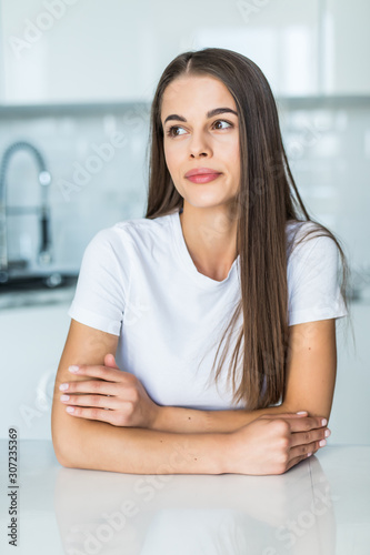 Young pretty woman sitting a table in the kitchen .