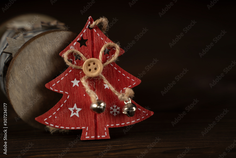 Red wooden Christmas tree and wooden vintage reel with silk ribbon with wooden stars on brown natural wooden background.