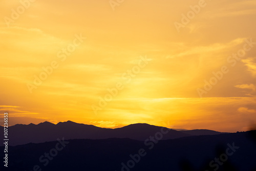 Beautiful silhouette of mountains during sunset with a golden sky © SPIX PRODUCTION
