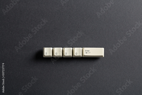Computer keyboard keys with 2020 enter written using the white buttons on a dark background. Holiday technology concept. New year 2020 card.