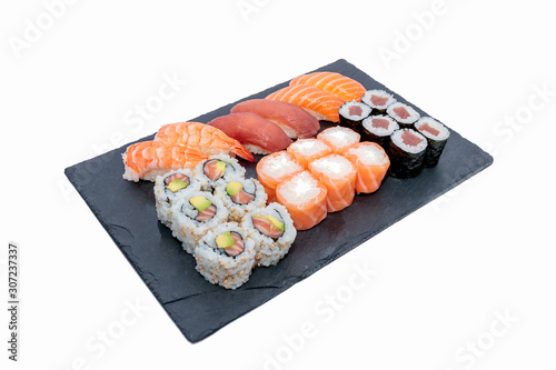 High angle shot of different sushi rolls on a black tray isolated on a white background