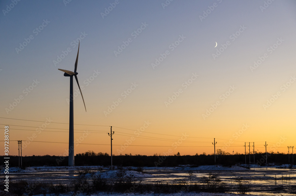 Windmill and power lines by sunset