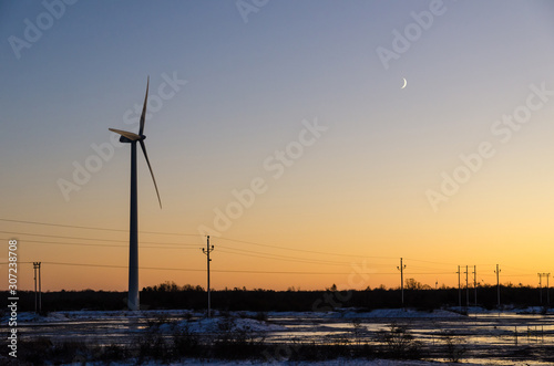 Windmill and power lines by sunset