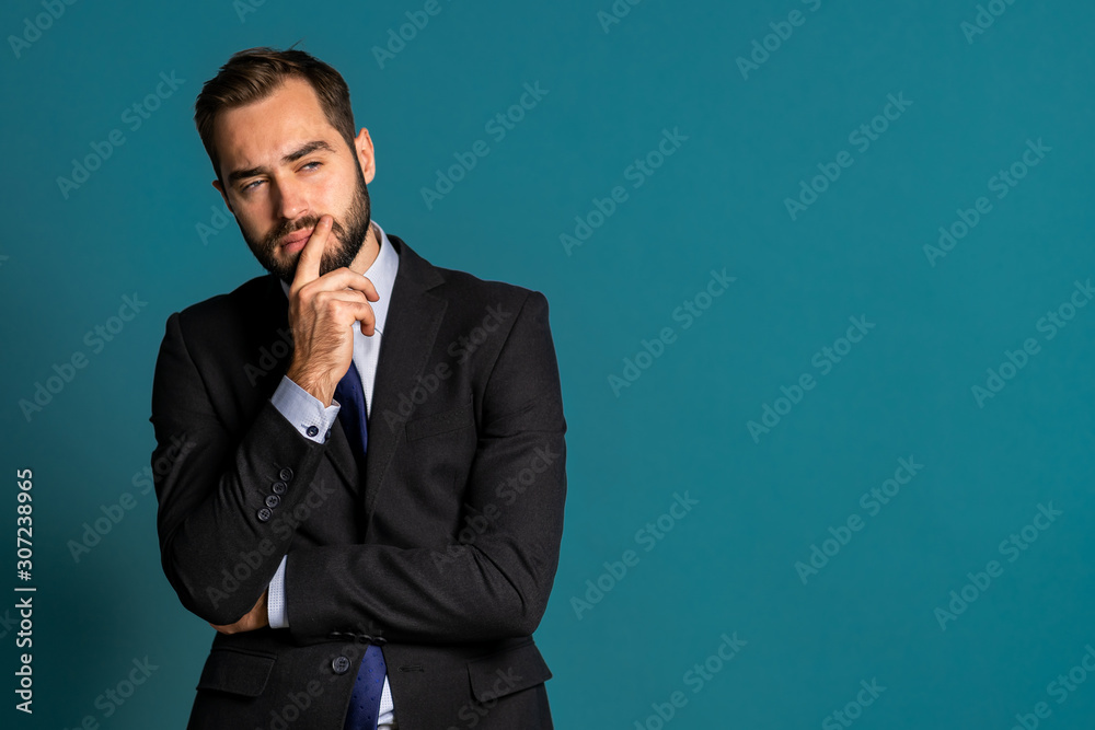 Serious thinking businessman looking around on blue background. Confused pensive face expressions. Handsome male model in corporate suit.