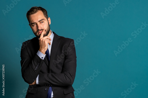 Serious thinking businessman looking around on blue background. Confused pensive face expressions. Handsome male model in corporate suit.